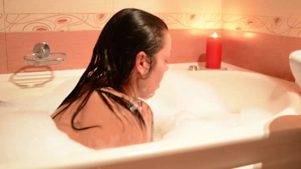 泡風呂にワインのグラスと美しい少女 大きな白いお風呂と彼の顔に喜び リラクゼーション コンセプト — ストック動画