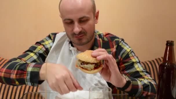 Young Man Eating Fast Food Hamburger Drinks Beer — Stock Video