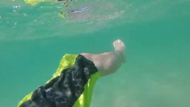 Gros plan des pieds flottant dans l'homme de l'océan se détendre dans l'eau tropicale bleue claire pendant les vacances d'été à la plage 