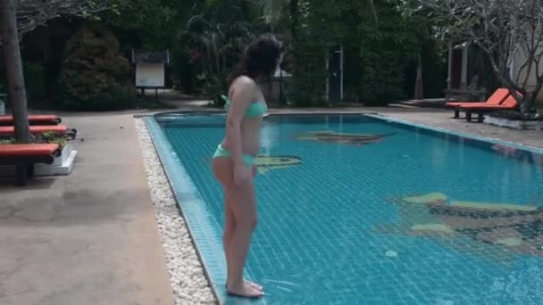 Brunette fille sautant dans la piscine 