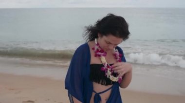 Plajda çiçekli mavi elbiseli boyunda esmer yürür