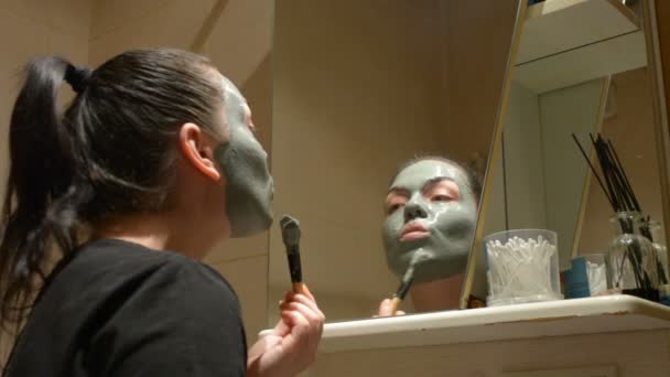 Menina Provoca Máscara Argila Rosto — Vídeo de Stock