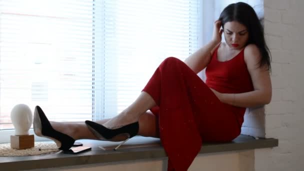 Κορίτσι Ένα Κόκκινο Φόρεμα Κάθεται Στο Περβάζι — Αρχείο Βίντεο