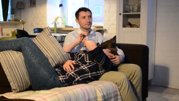 Unga par med smartphones liggande på soffan. Man och kvinna använda gadget att umgås, prata med varandra. Par dåre runt och kysser varandra. — Stockvideo