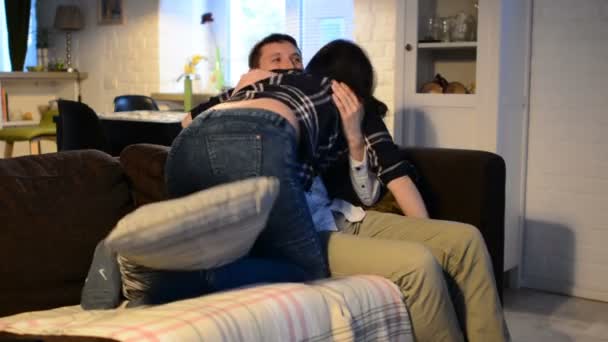 Junges Paar mit Smartphones auf dem Sofa liegend. Mann und Frau nutzen Gadget, um Zeit zu verbringen, miteinander zu reden. Paar albert herum und küsst sich. — Stockvideo