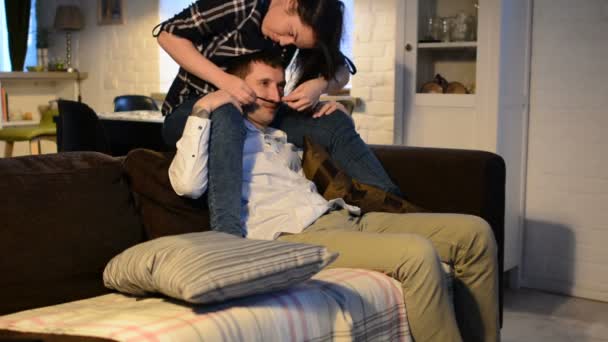 Jeune couple avec smartphones couché sur le canapé. Homme et femme utilisent gadget pour passer du temps, parler entre eux. Couple imbécile et s'embrasser . — Video