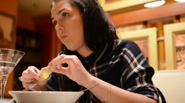 Zarif kız akıllı telefon tarama rahat İtalyan restoranı tabloda başına oturmuş. Olumlu ruh hali içinde genç Kafkas kadın akşam yemeğinin tadını çıkarın ve akıllı telefon iletişim