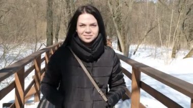 Bir kış parkta şık genç güzel kadın portresi kadar karlı arka plan üzerinde kapatın. Kış park kamera için arıyorum. Kar yağıyor. açık havada. güzel genç kadın bir kışın yürüyor