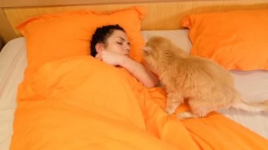 Bir kız ile bir kedi yatakta uyuyor. 4k