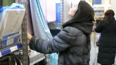 Güzel çekici genç kadın mağaza raflarında kilim seçer. Tüketim kavramı.
