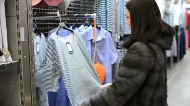 Alışveriş kız. Depodaki güzel bir kadın portresi. Kırmızı dudaklar bir giyim mağazası ile genç bir esmer kız portresi. O bir elbise prova için seçti. Şık giysiler içinde moda esmer