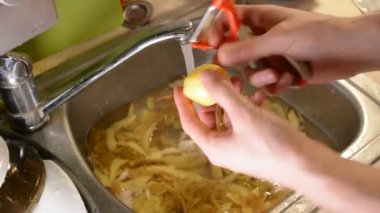 Lavaboya su ile bir bıçakla peeling ham patates erkek eller