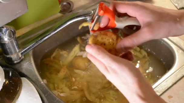 男性手去皮用刀在水槽与水的生土豆 — 图库视频影像