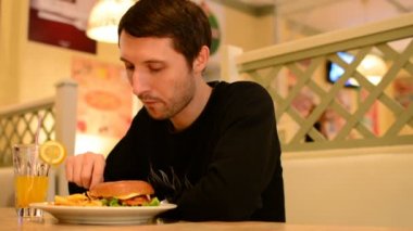 Bir adam bir restoranda bir Burger ve Limonata içer