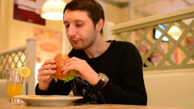 Bir adam bir restoranda bir Burger ve Limonata içer