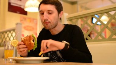 Bir adam bir restoranda bir Burger ve Limonata içer