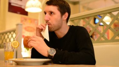 Bir adam bir restoranda bir Burger ve Limonata içer