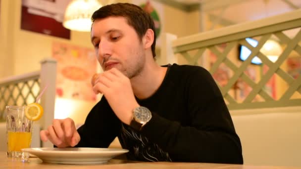 Un homme a un hamburger dans un restaurant et boit de la limonade — Video