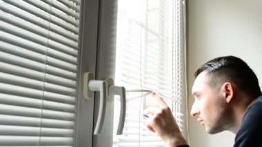 Perdeleri sokağa pencereden dışarı bakarak, casusluk adam. şüpheli