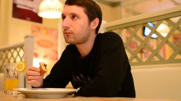Ein Mann hat einen Burger im Restaurant und trinkt Limonade — Stockvideo