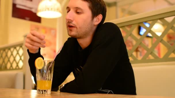 Un uomo ha un hamburger in un ristorante e beve limonata — Video Stock
