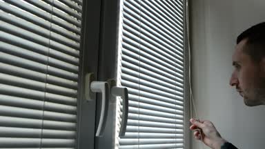 Perdeleri sokağa pencereden dışarı bakarak, casusluk adam. şüpheli