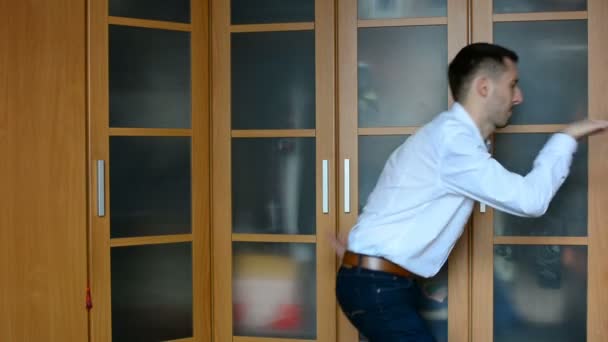 Mladý muž tančí doma proti skříni — Stock video