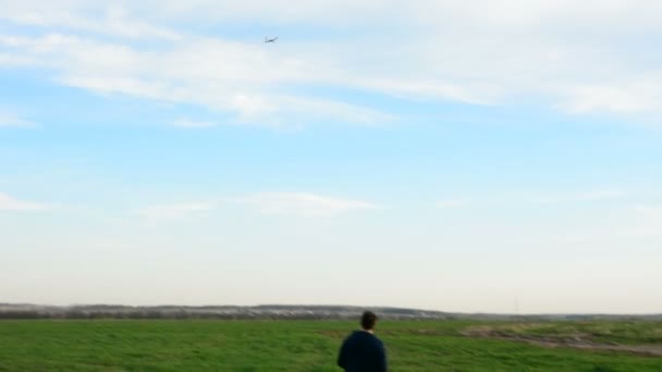 Joven controlando dron en el campo al atardecer . — Vídeo de stock