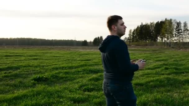 Junger Mann steuert Drohne in Feld bei Sonnenuntergang. — Stockvideo