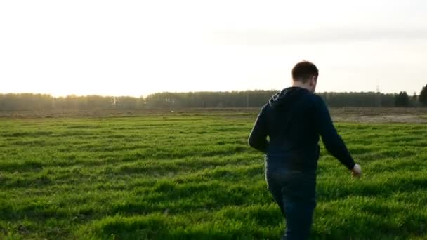 Joven controlando dron en el campo al atardecer . — Vídeo de stock