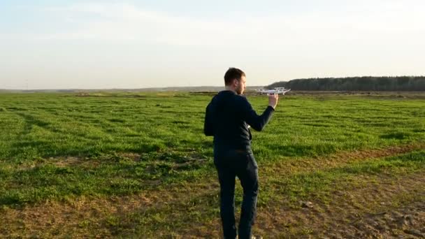 Mladý muž ovládání drone v poli při západu slunce. — Stock video