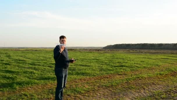 Jovem controlando drone no campo ao pôr-do-sol . — Vídeo de Stock