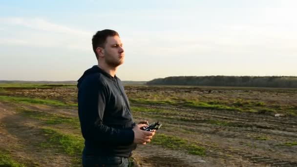 Joven controlando dron en el campo al atardecer . — Vídeo de stock