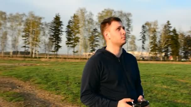 Joven controlando dron en el campo al atardecer . — Vídeo de stock