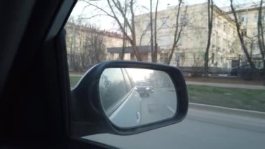 Dikiz aynasından arabanın görüntüsü görünüyor. Yoğun şehir sokaklarında araba sürüyorum..