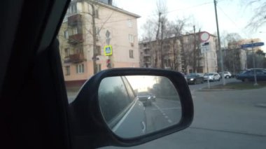 Dikiz aynasından arabanın görüntüsü görünüyor. Yoğun şehir sokaklarında araba sürüyorum..
