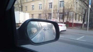 Dikiz aynasından arabanın görüntüsü görünüyor. Yoğun şehir sokaklarında araba sürüyorum..