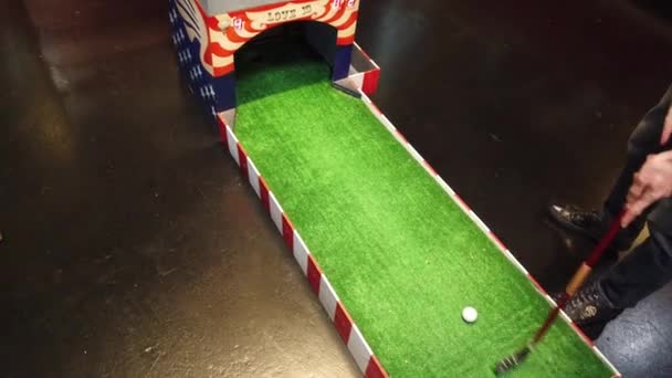 Jugando mini golf. Una persona golpeando la pelota de golf y golpea el objetivo — Vídeo de stock