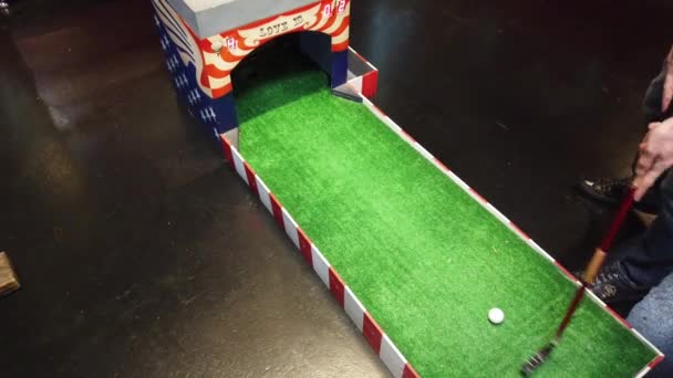Minigolf spielen. eine Person schlägt den Golfball und trifft das Ziel — Stockvideo