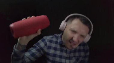 Evde pembe kulaklıklarla müzik dinleyen bir adam.