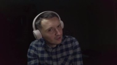 Evde pembe kulaklıklarla müzik dinleyen bir adam.