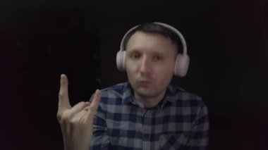 Evde pembe kulaklıklarla müzik dinleyen bir adam.