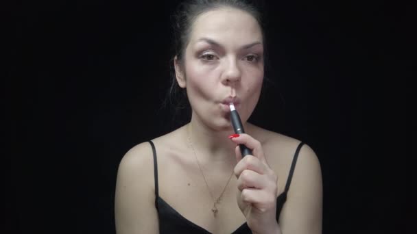 Detailní záběr hezká žena s elektronickými cigaretami Iqos. Mladá žena kouření tabák tyčinka topení a vydechující kouř.