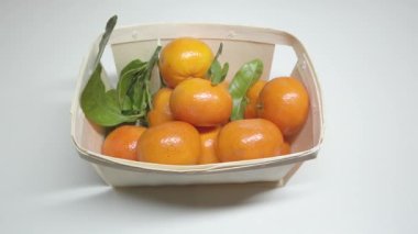 Tahta sepetteki mandalinalar, bir insan elleriyle mandalinaya dokunur.