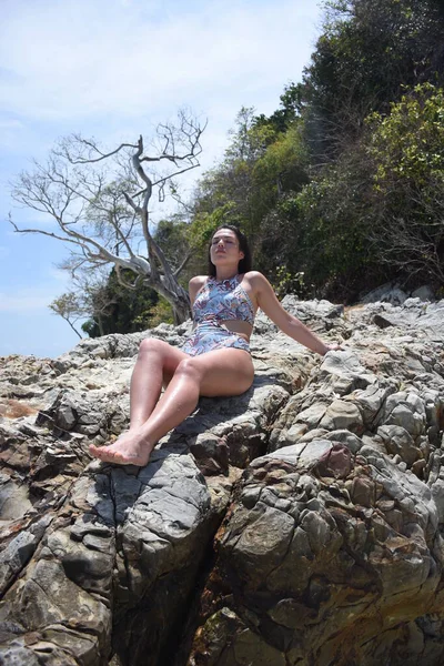 少女は岩の多い海岸に腰を下ろしている 岩の上の水着の女の子 — ストック写真