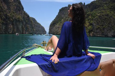 Phi Phi adasının yeşil kayalarının etrafındaki bir teknenin pruvasında güzel bir kız.