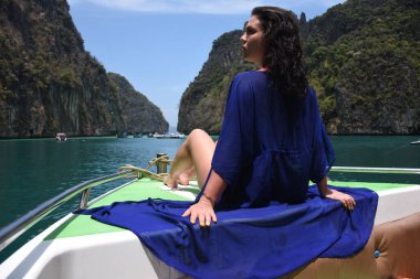 Phi Phi adasının yeşil kayalarının etrafındaki bir teknenin pruvasında güzel bir kız.