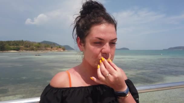 Chica Para Muelle Contra Mar Azul Come Una Pequeña Piña — Vídeo de stock