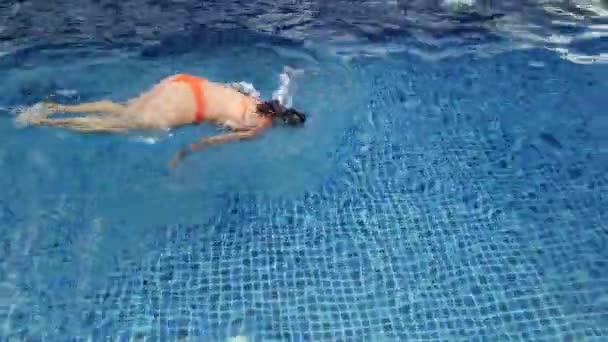 Vacker flicka i orange baddräkt simmar i blå pool — Stockvideo