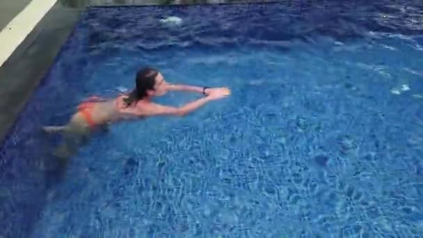 Menina bonita em maiô laranja nada na piscina azul — Vídeo de Stock